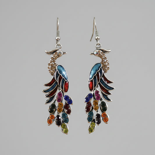 Multicolored feather-shaped earrings on a wooden stick with a blurred background