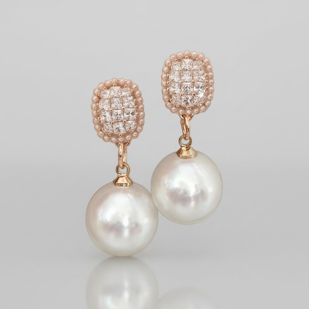 Pearl earrings with gold and diamond-like top elements on a white background