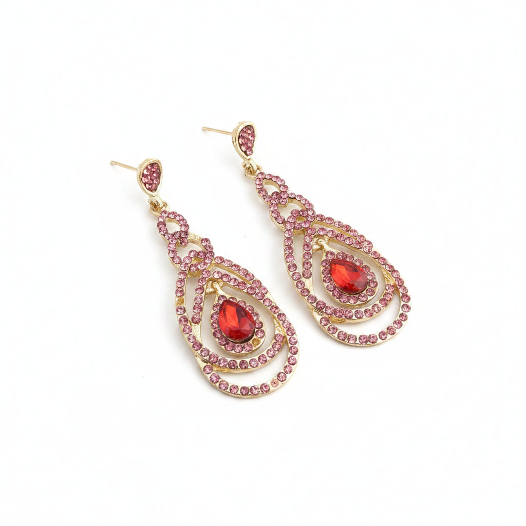 Gold earrings with pink and red gemstones on a gray background