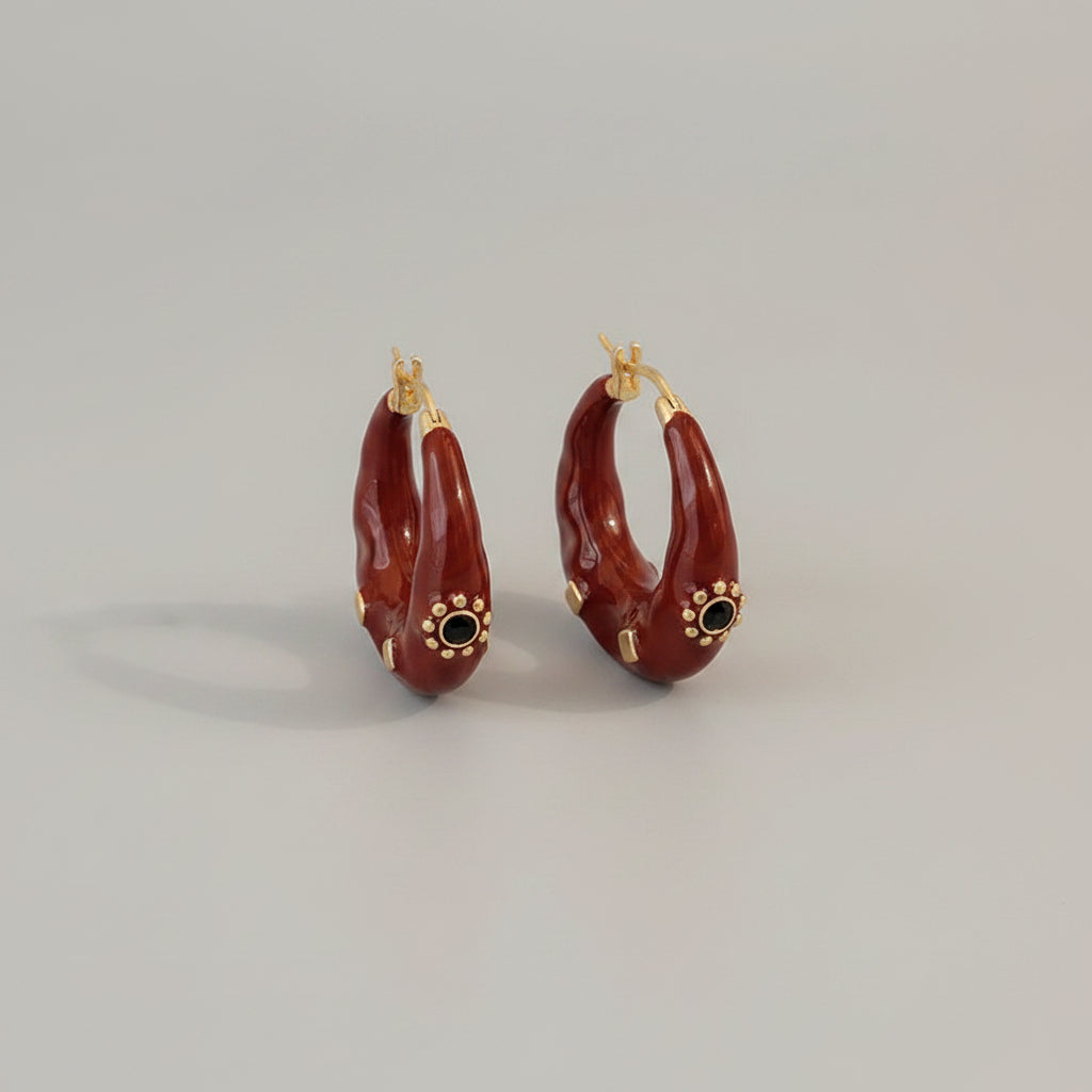 Red hoop earrings with gold accents on a black surface