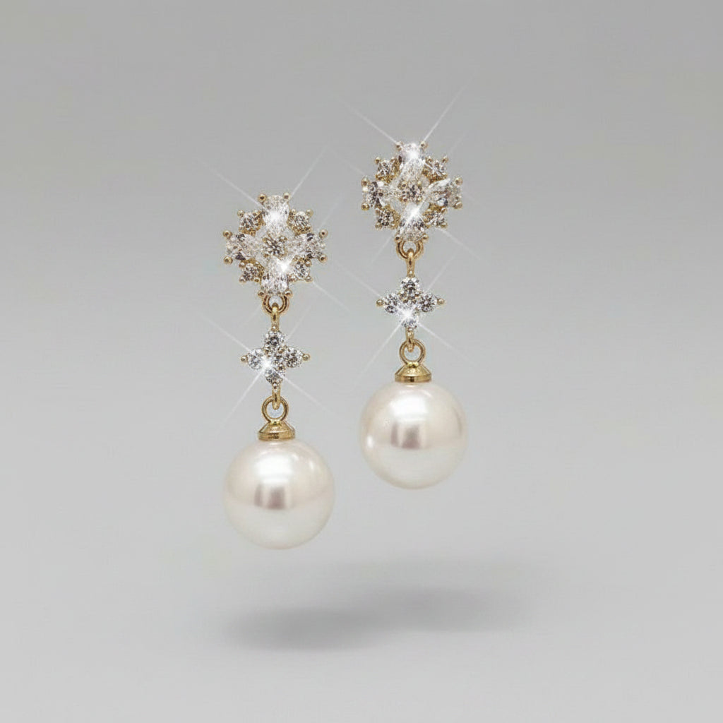 Pearl earrings with star-shaped crystals held by a hand against a neutral background