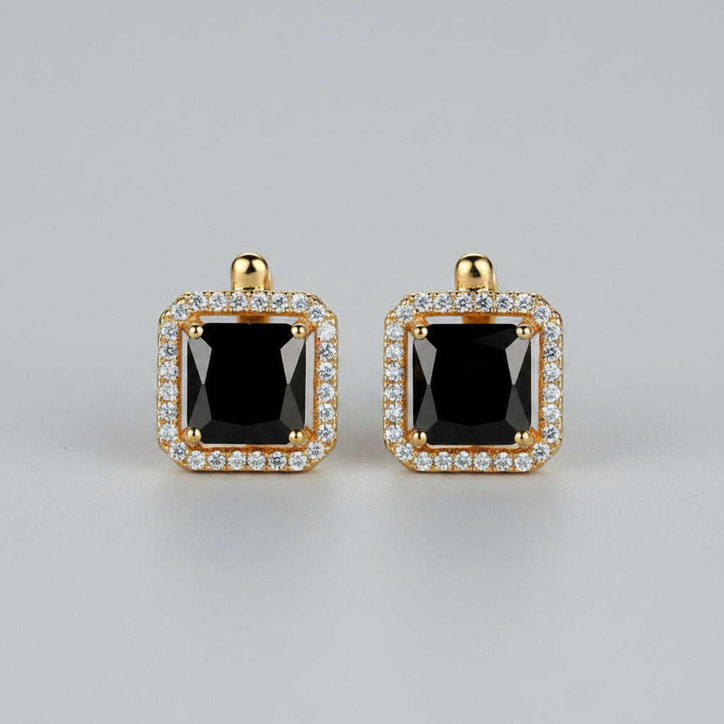 Gold-framed black square gemstone earrings on a light background