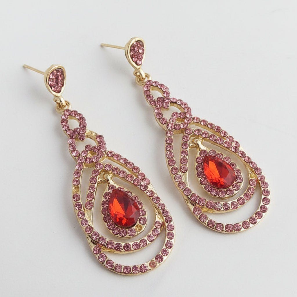 Gold earrings with pink and red gemstones on a gray background