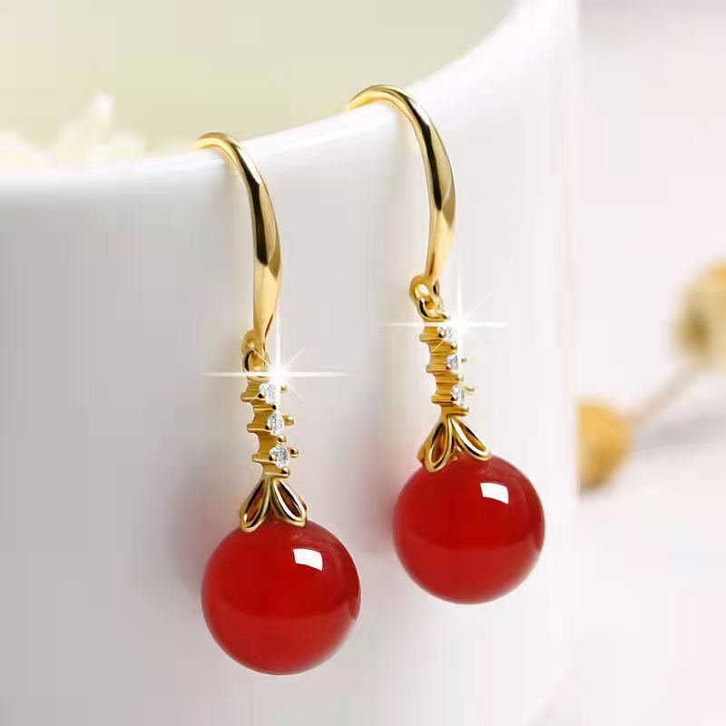 Gold earrings with red gemstones on a white background