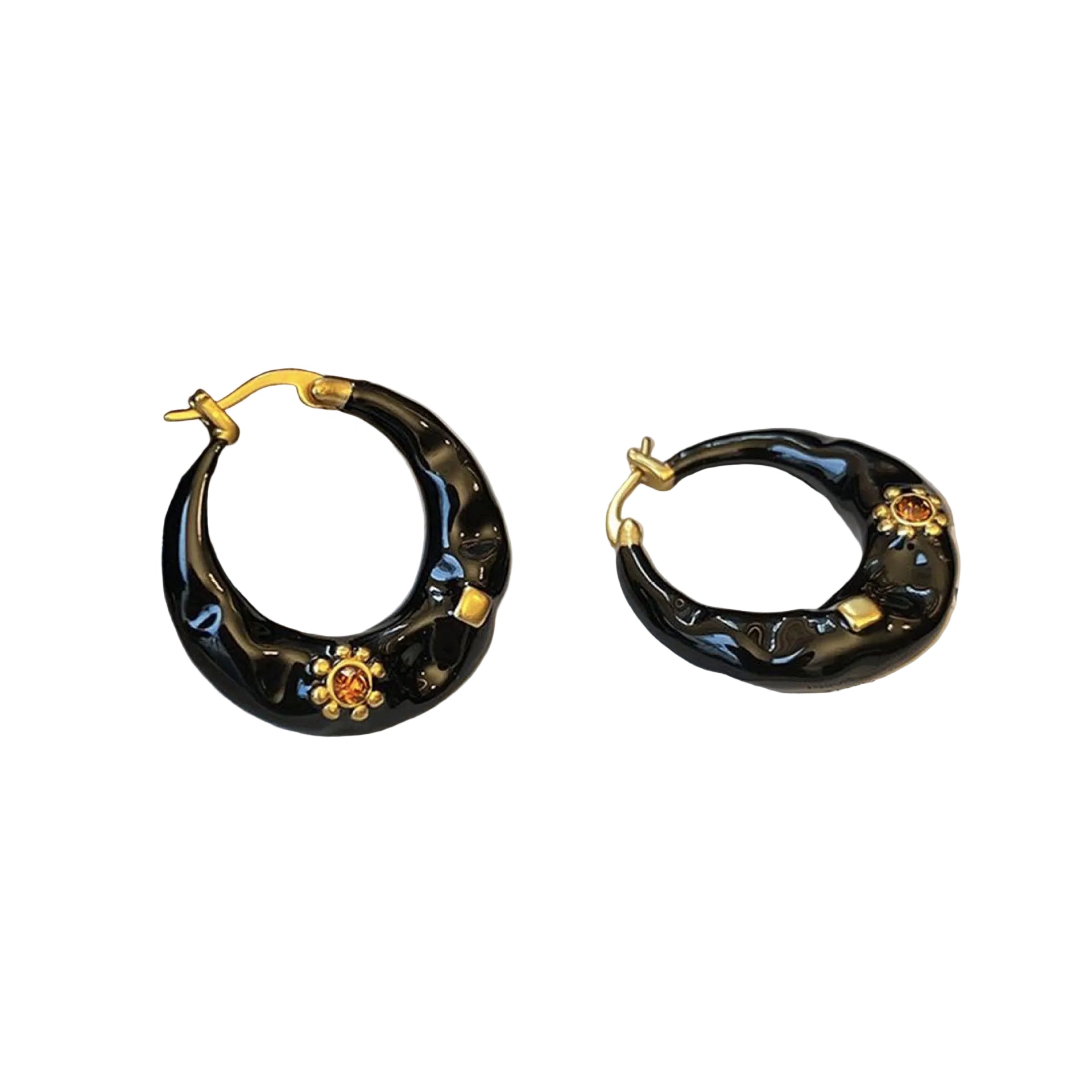 Black hoop earrings with gold accents on a gray surface.