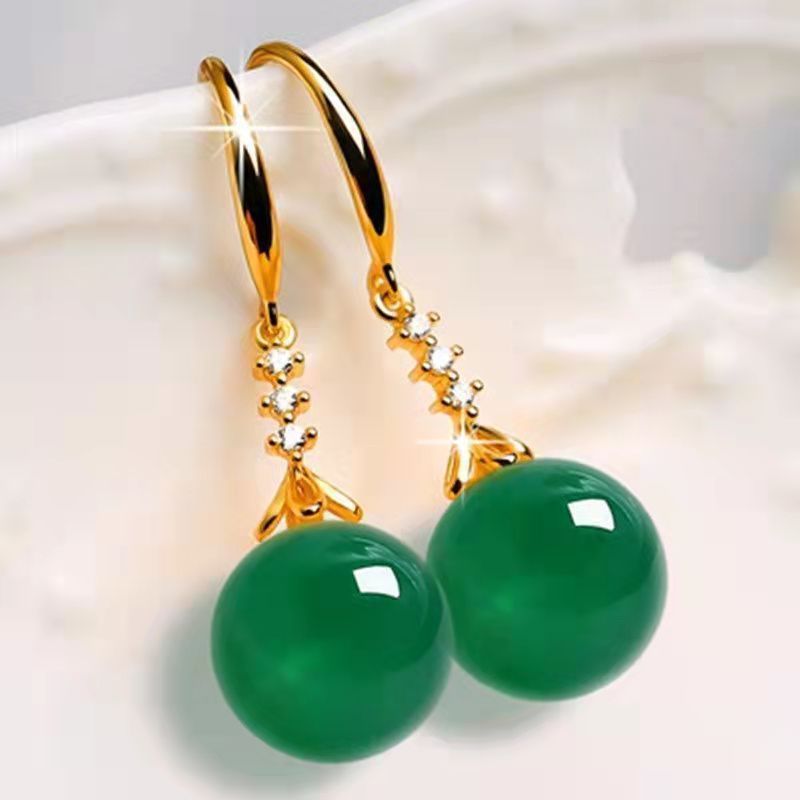 Gold earrings with green gemstones on a white background