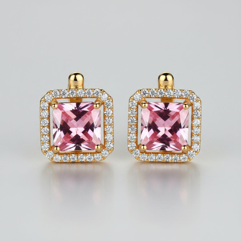 Gold earrings with pink gemstones on a light background