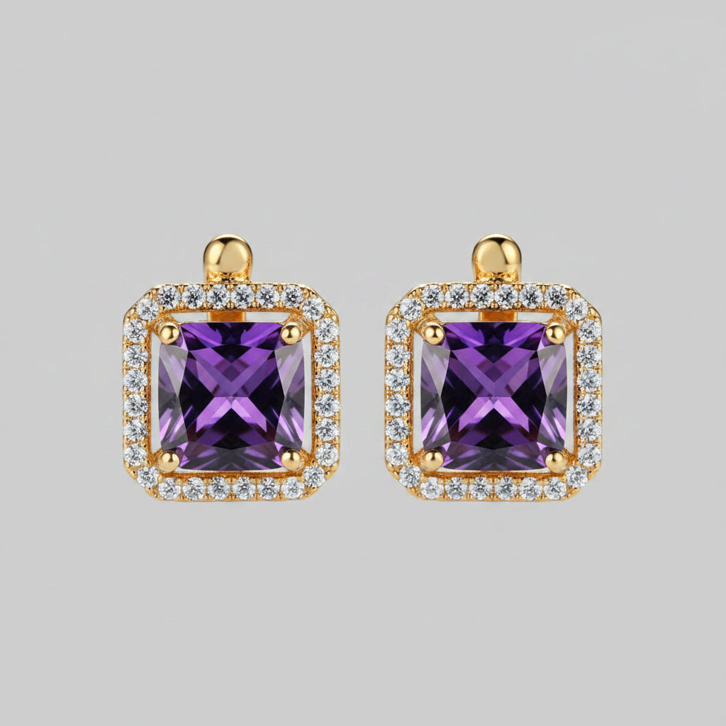 Gold earrings with purple gemstones on a light background