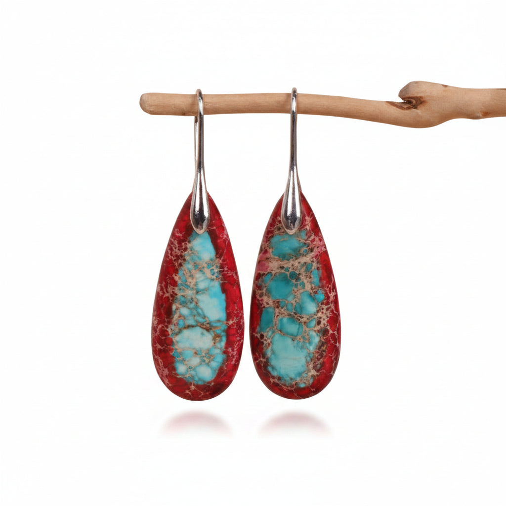 Teardrop-shaped earrings with turquoise and red pattern on a beige background