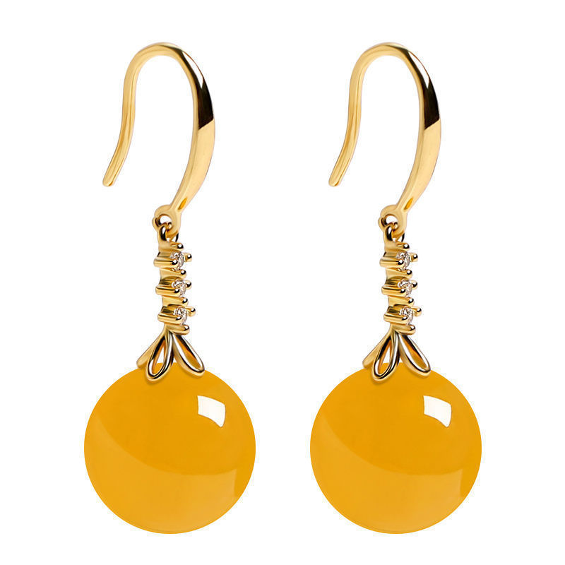 Gold earrings with yellow round stones on a white background