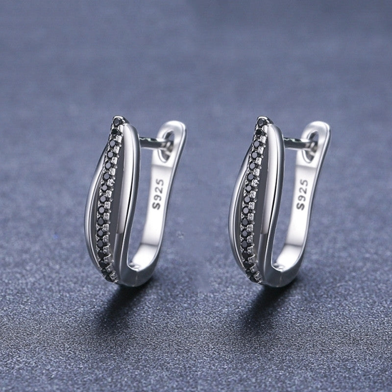 Pair of silver hoop earrings with black stones on a dark gray background
