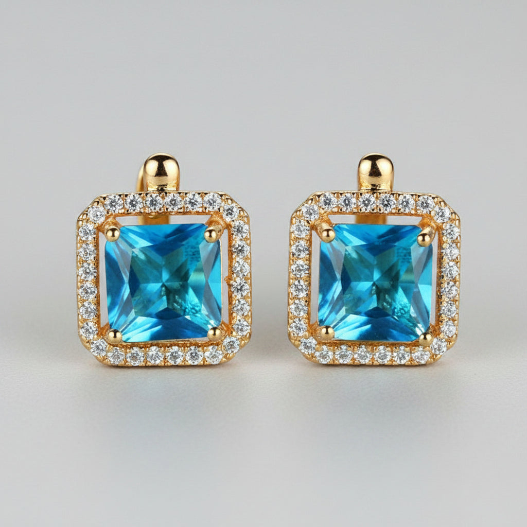 Gold earrings with blue gemstones on a neutral background