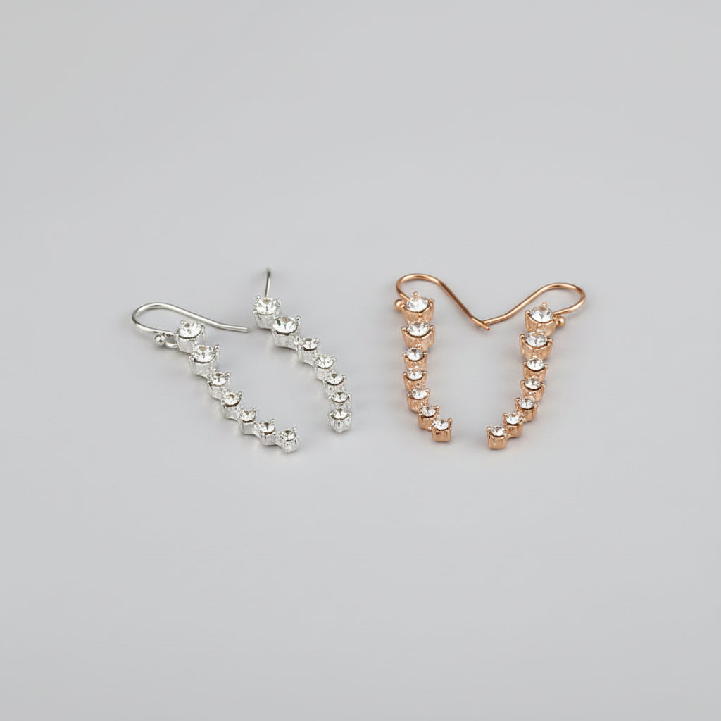 Two pairs of earrings, one silver and one rose gold, on a white surface.
