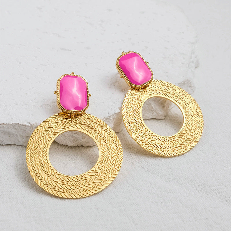 Gold earrings with pink stones on a light gray background