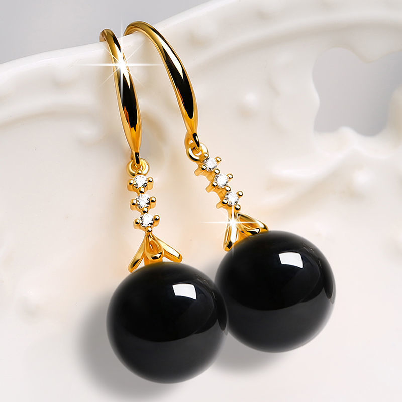 Gold earrings with black beads on a white background