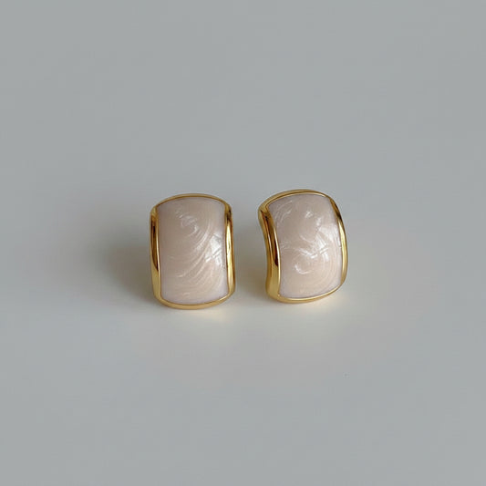 Gold-framed earrings with a textured stone-like center on a light gray background