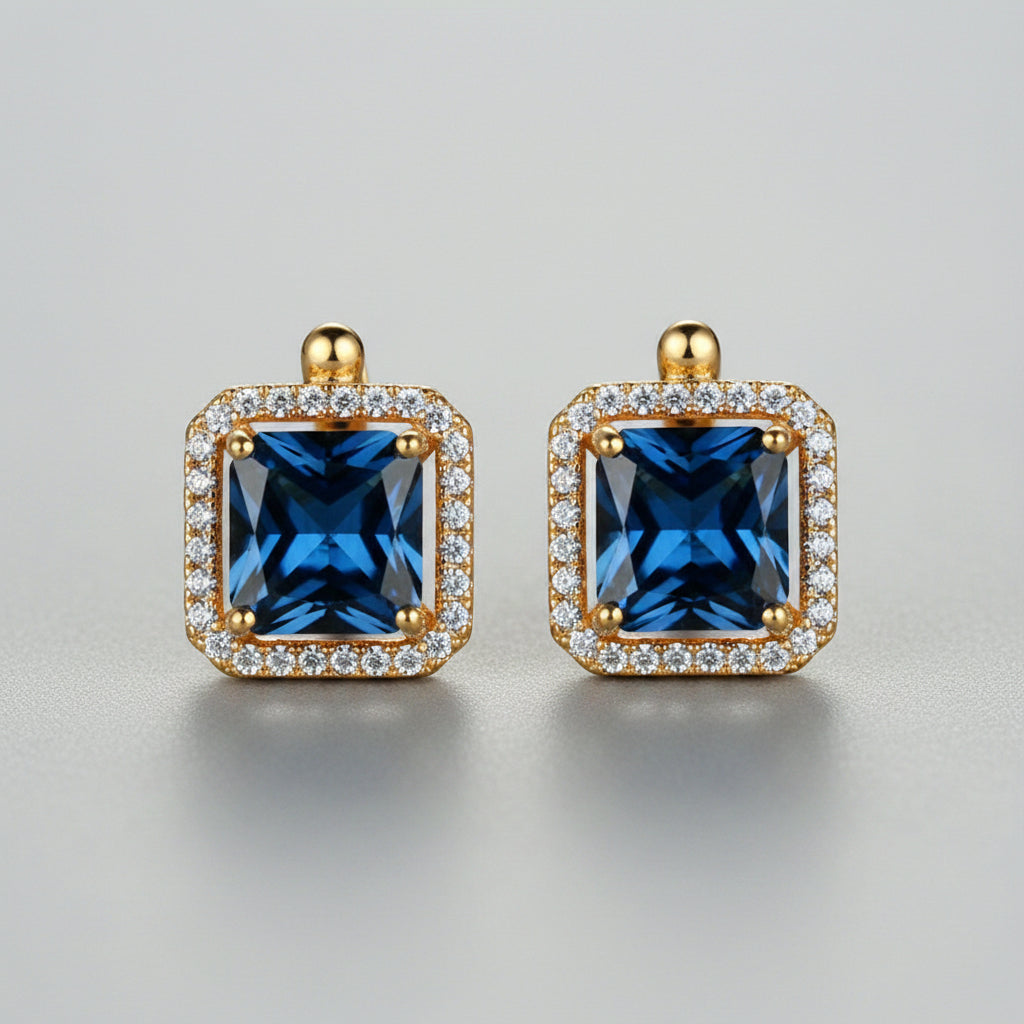 Gold-framed blue gemstone earrings on a neutral background