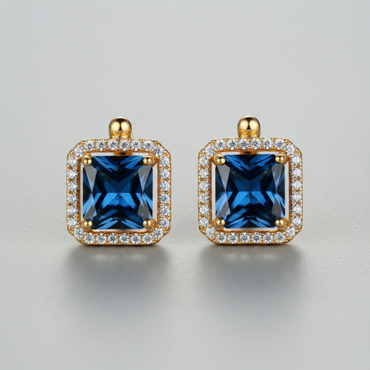 Gold-framed blue gemstone earrings on a neutral background