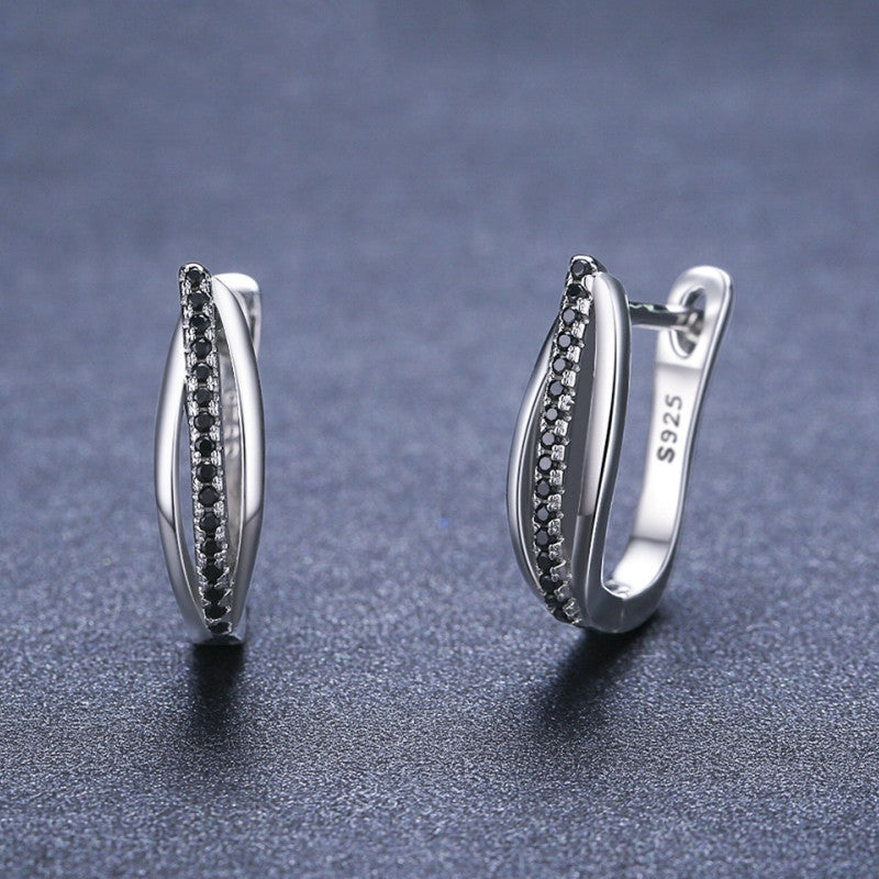 Pair of silver hoop earrings with black stones on a dark gray background