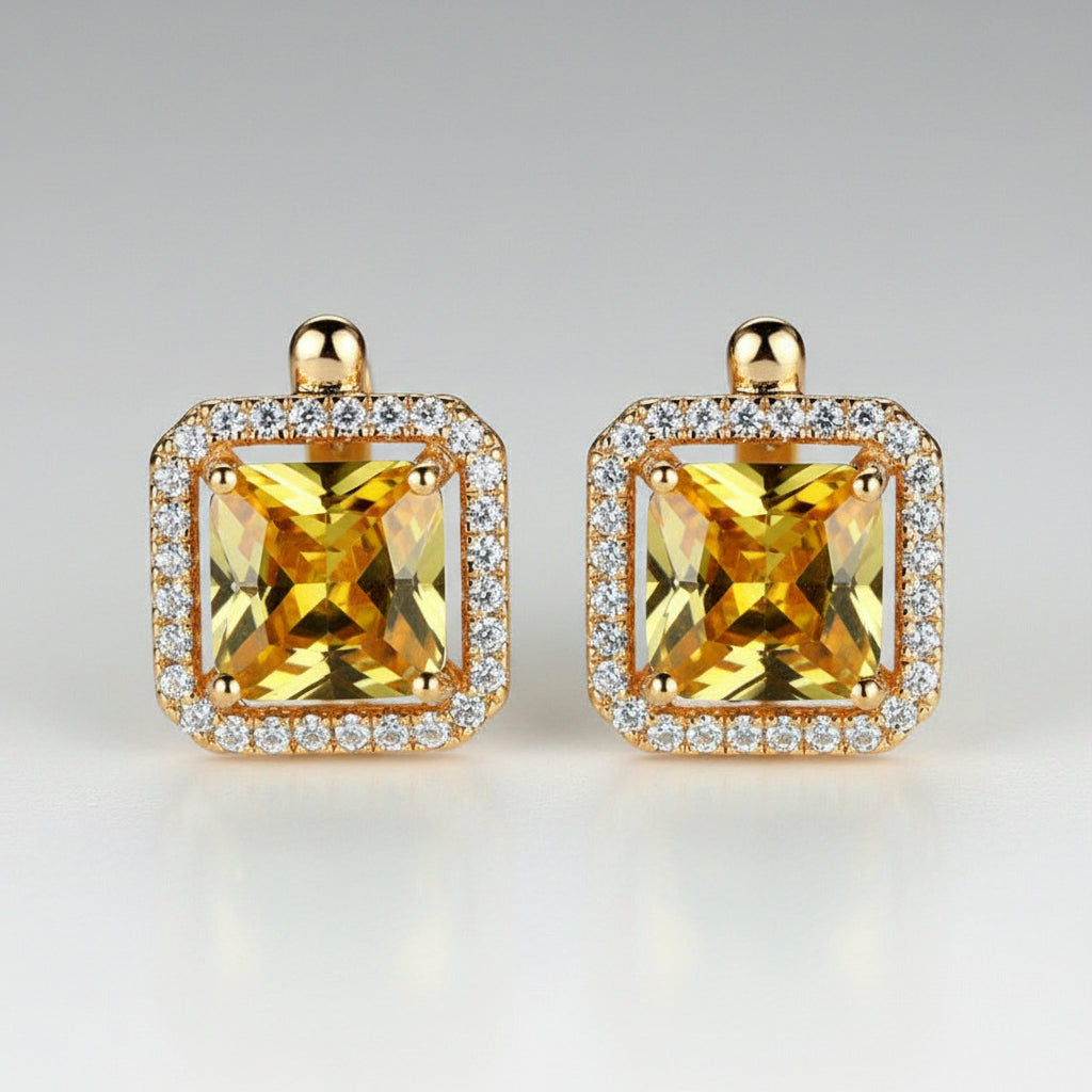 Gold earrings with yellow gemstones on a light background