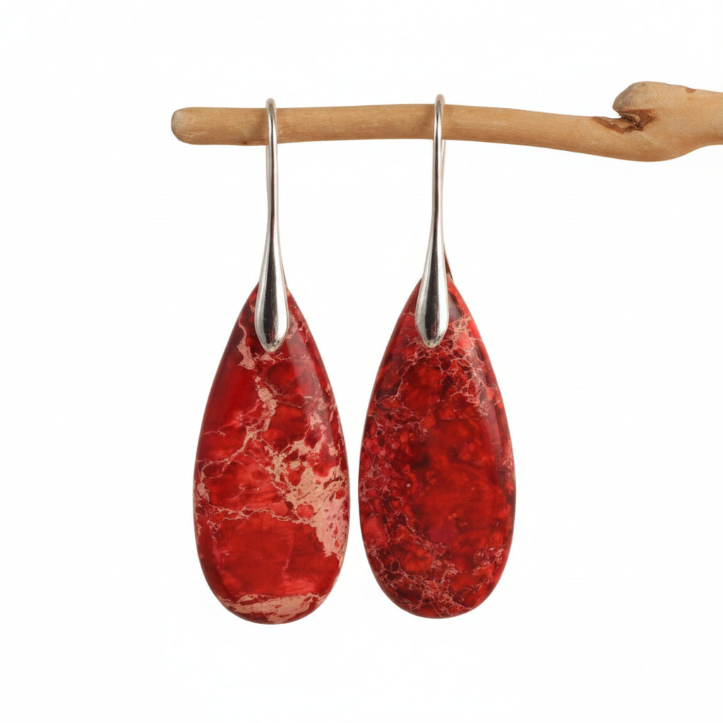 Red teardrop earrings with silver hooks on a beige background