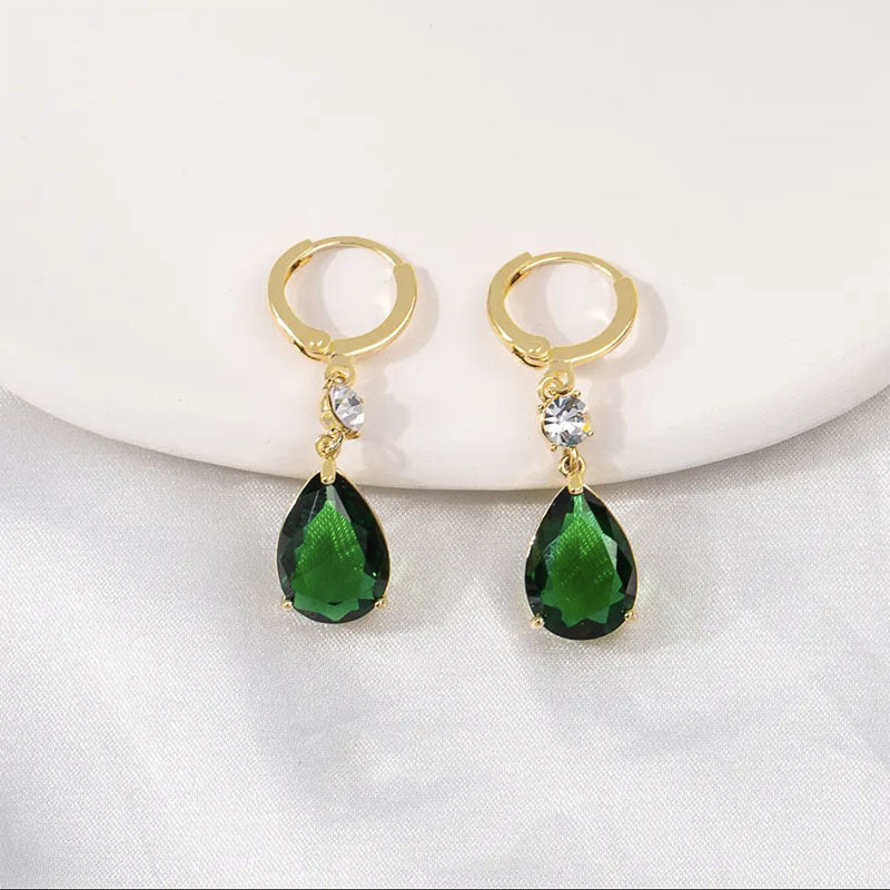 Gold hoop earrings with green teardrop-shaped gemstones on a white background