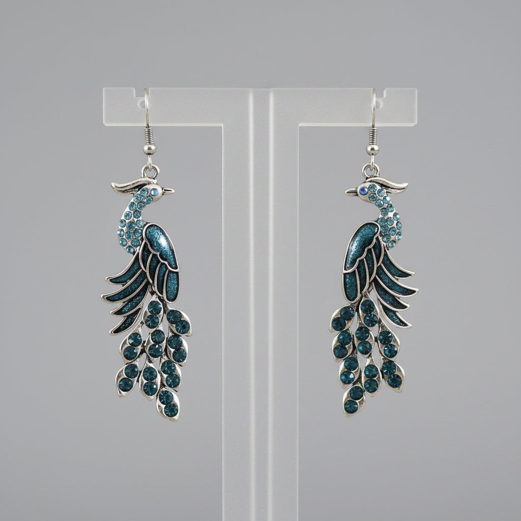 Pair of peacock feather earrings on a wooden stick with a blurred background