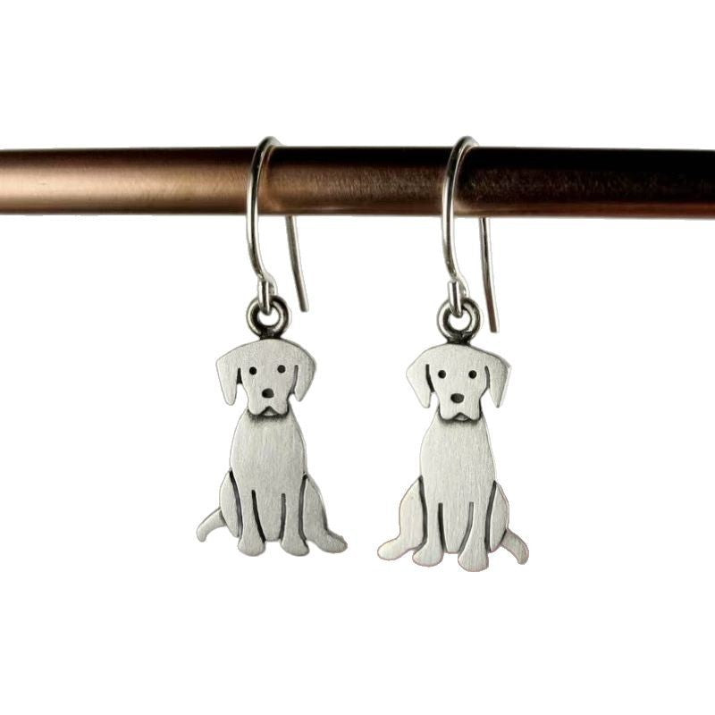 Silver dog-shaped earrings hanging from a rod on a white background