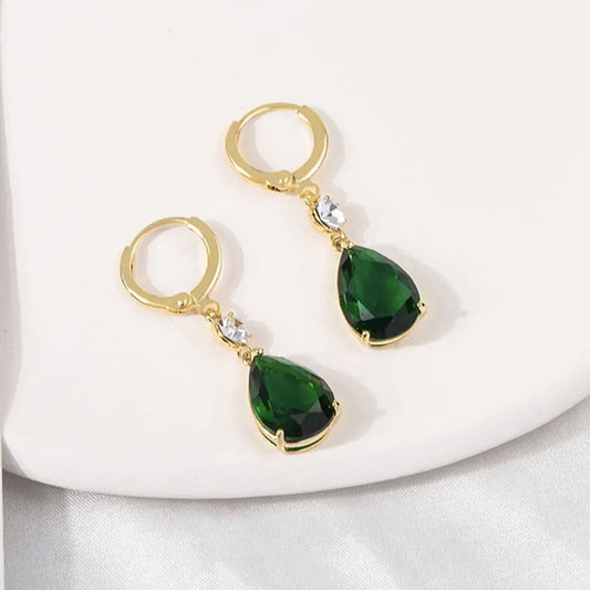 Gold earrings with green teardrop stones on a white background