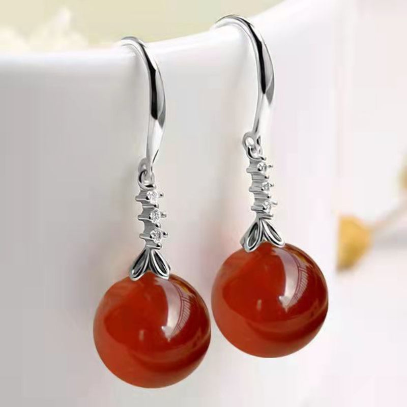 Silver earrings with red beads on a white background
