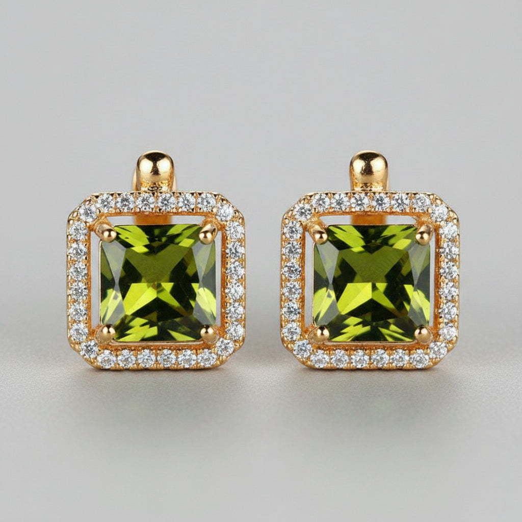 Gold earrings with green gemstones on a light background