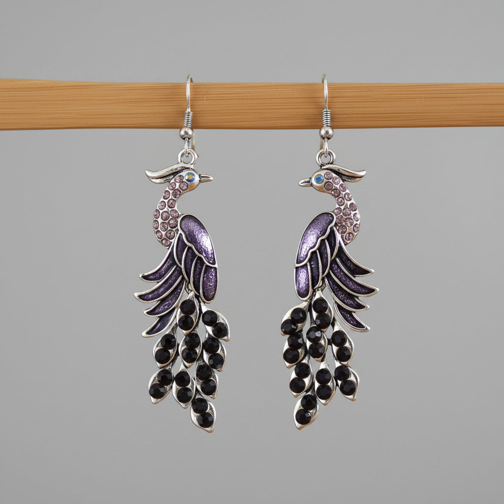 Peacock feather-shaped earrings on a wooden stick with a blurred background