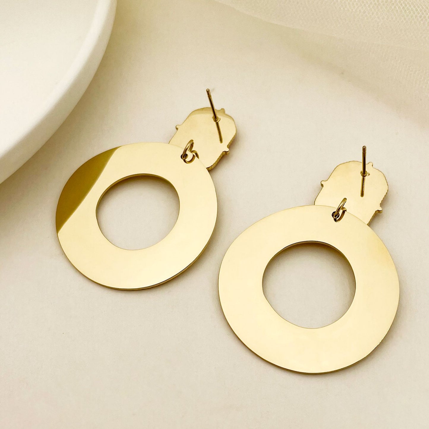Gold hoop earrings on a beige background